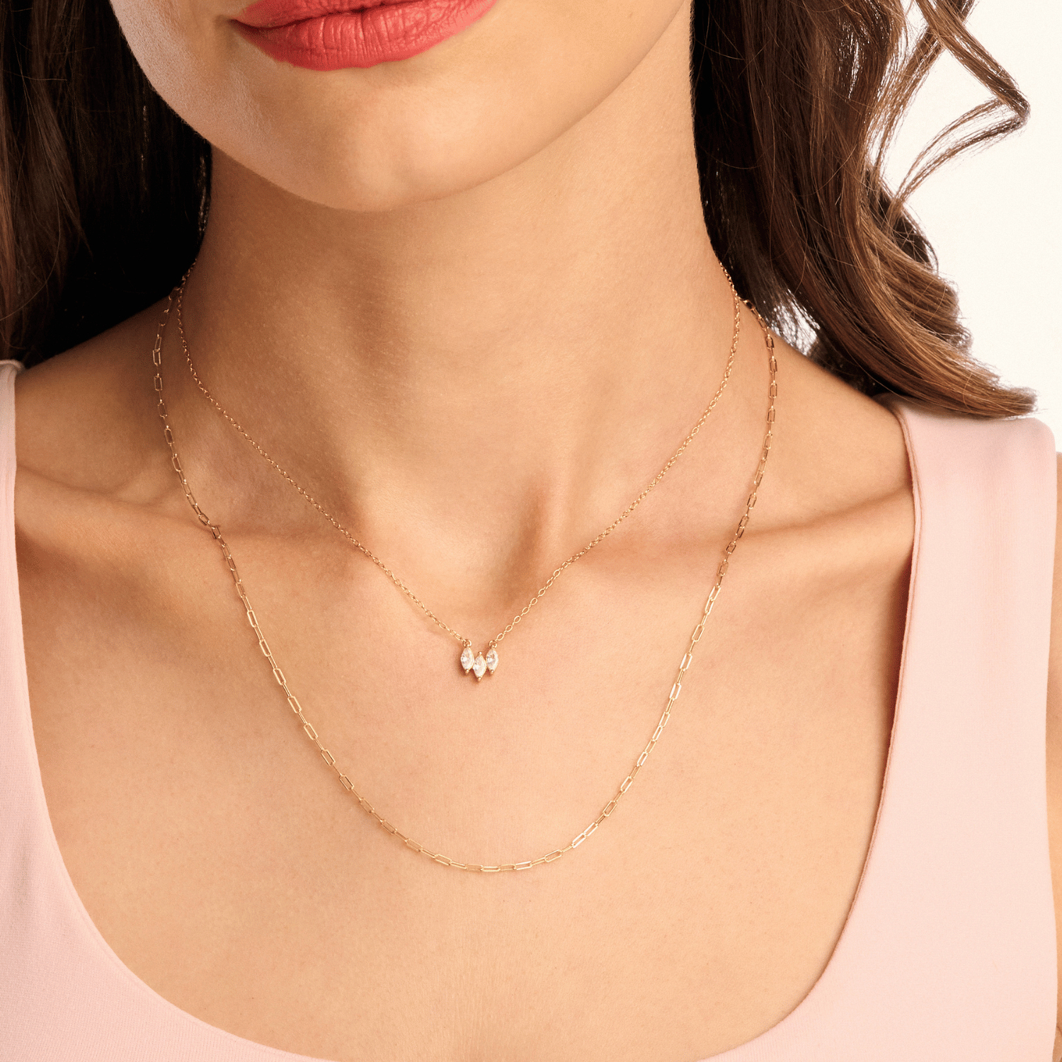 Model wearing a long gold paperclip necklace layered with a shorter necklace, showcasing a chic, modern, and stylish stacked look