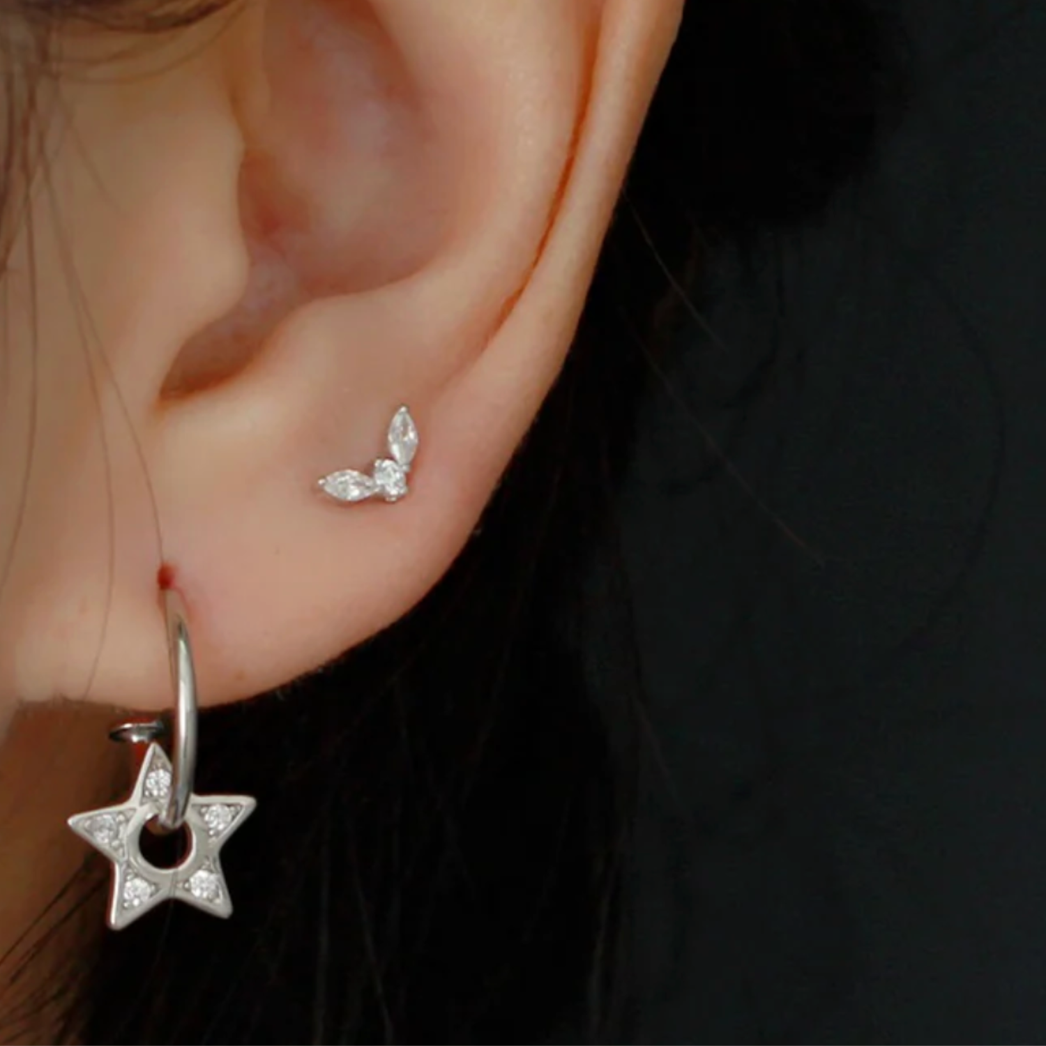 Model wearing Silver star-shaped earring with a butterfly earring in second piercing