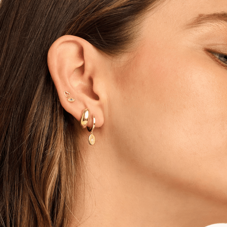 Model wearing Vesper Huggie Earrings, showcasing their gold-plated oval drop and delicate star design for a chic, celestial-inspired look