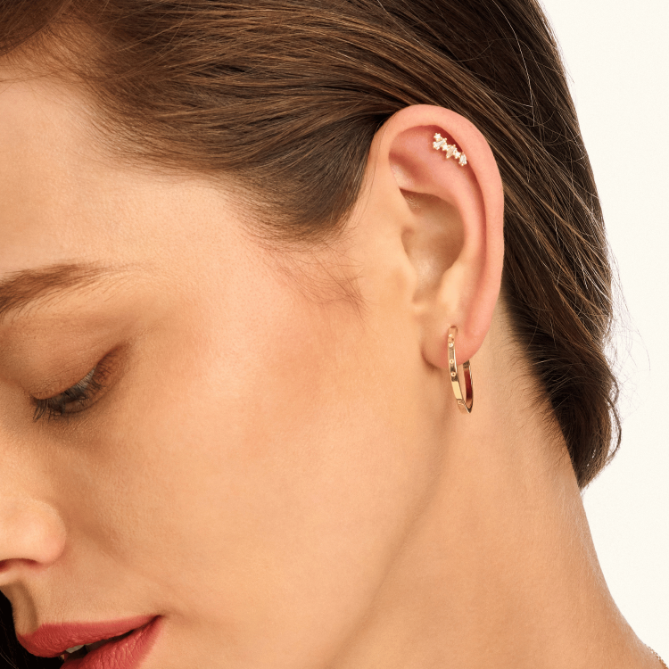 Model wearing gold decorative hoop earrings, showcasing their intricate design and elegant shine. Perfect for a chic statement or stylish stacking.