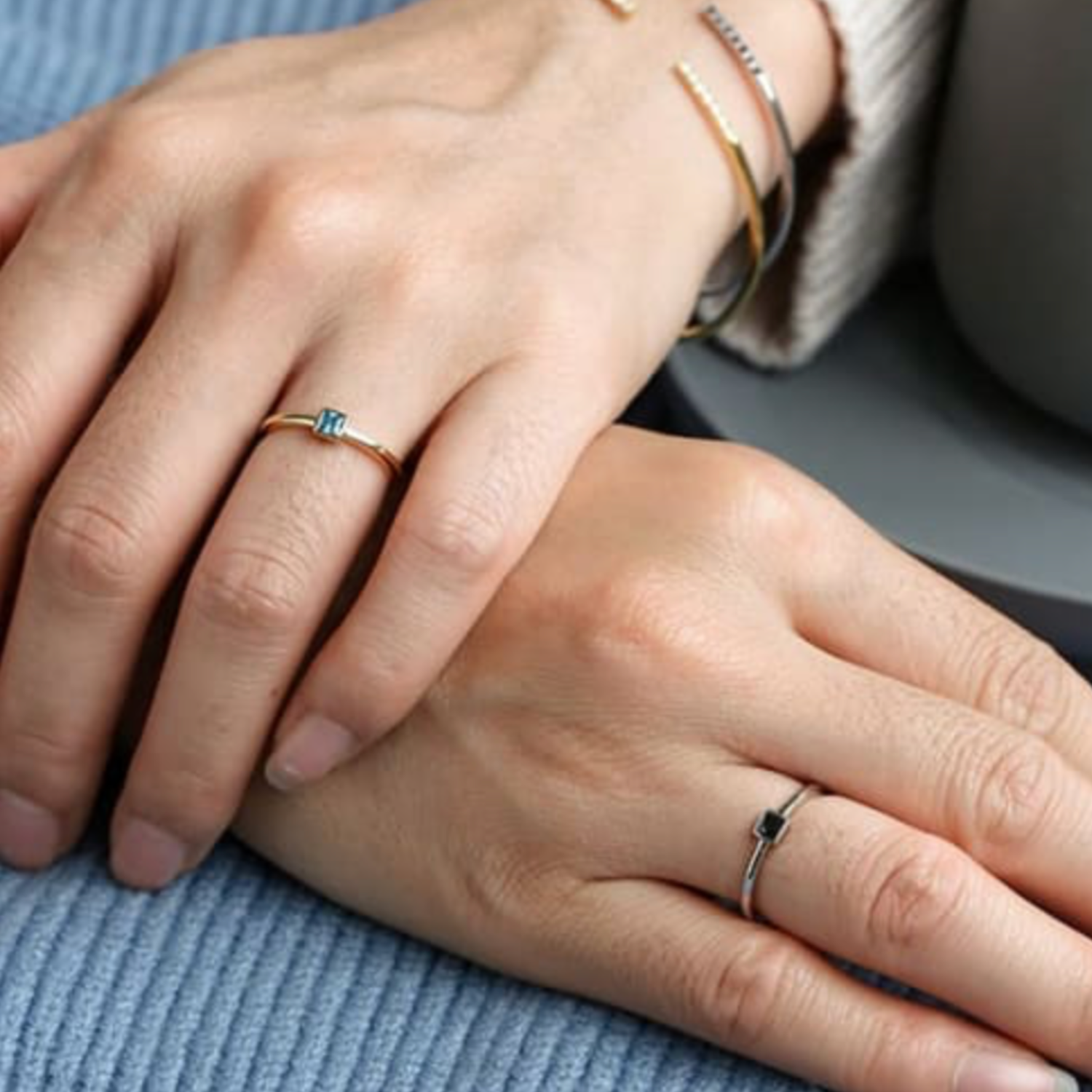 Close-up of two hands with rings on a blue fabric background