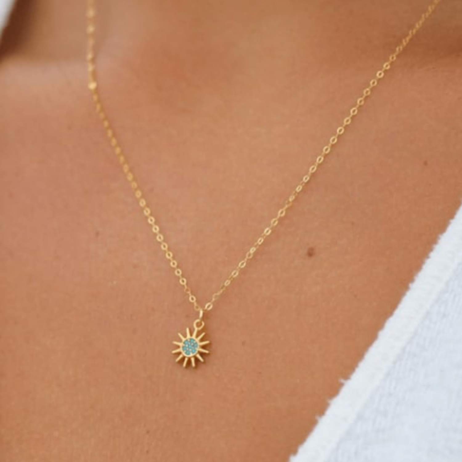 Gold necklace with a sun pendant on a model's neck