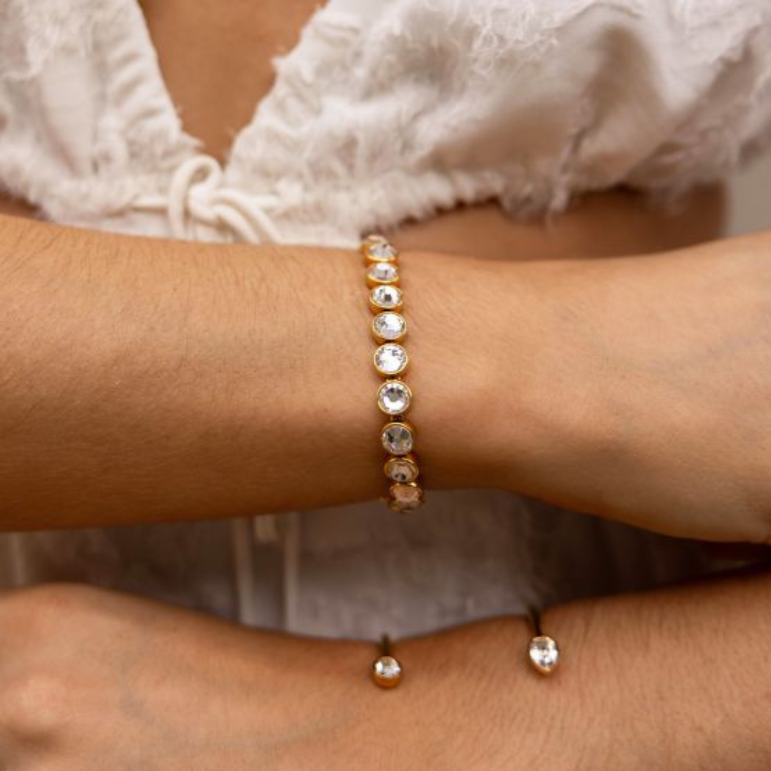 Close-up of a wrist wearing a gold bracelet with clear crystals.