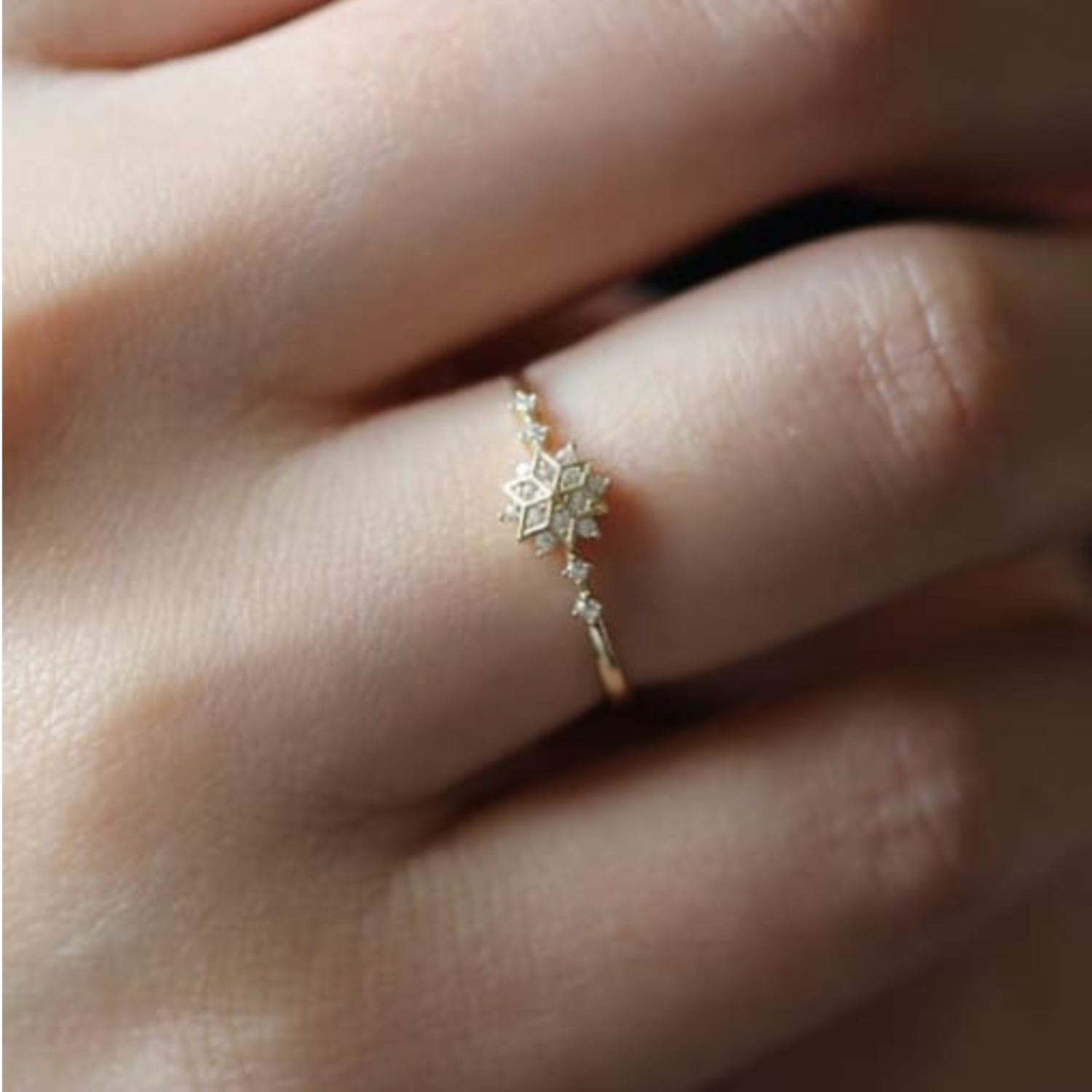 Gold ring with diamond-like stones on a finger