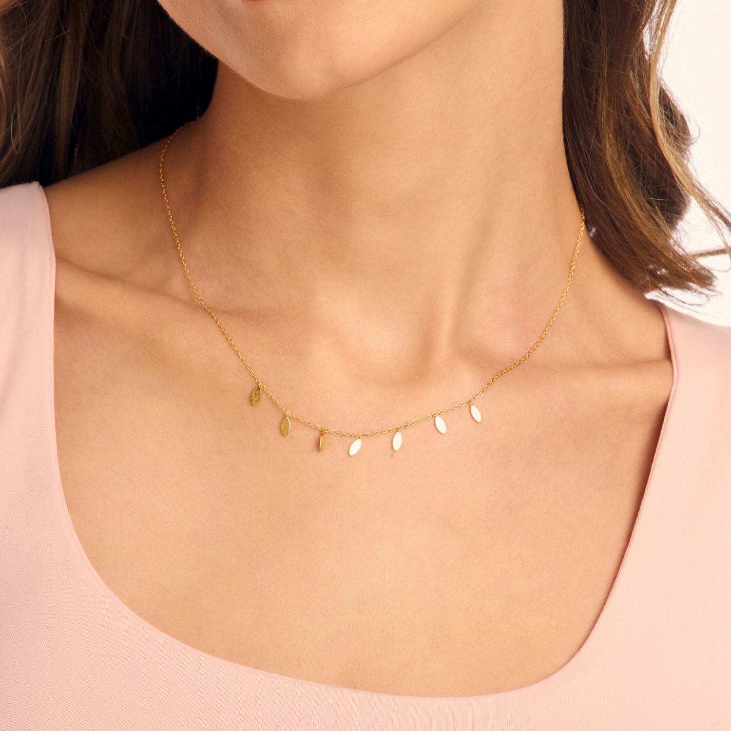 Model wearing a gold petal drop necklace, featuring delicate petal charms along a fine chain for an elegant, feminine, and timeless look