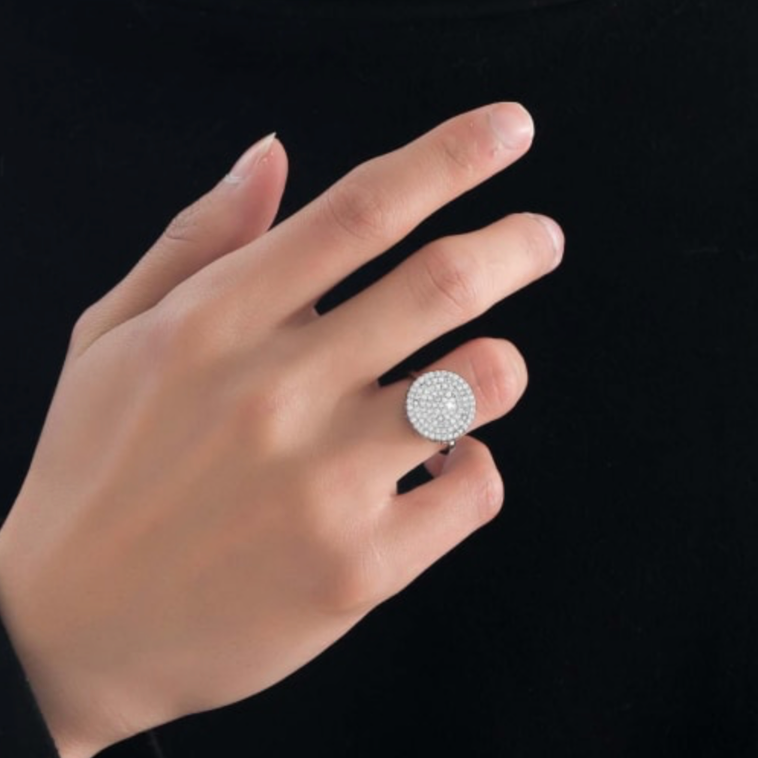 Hand wearing a silver ring with gemstones on a black background