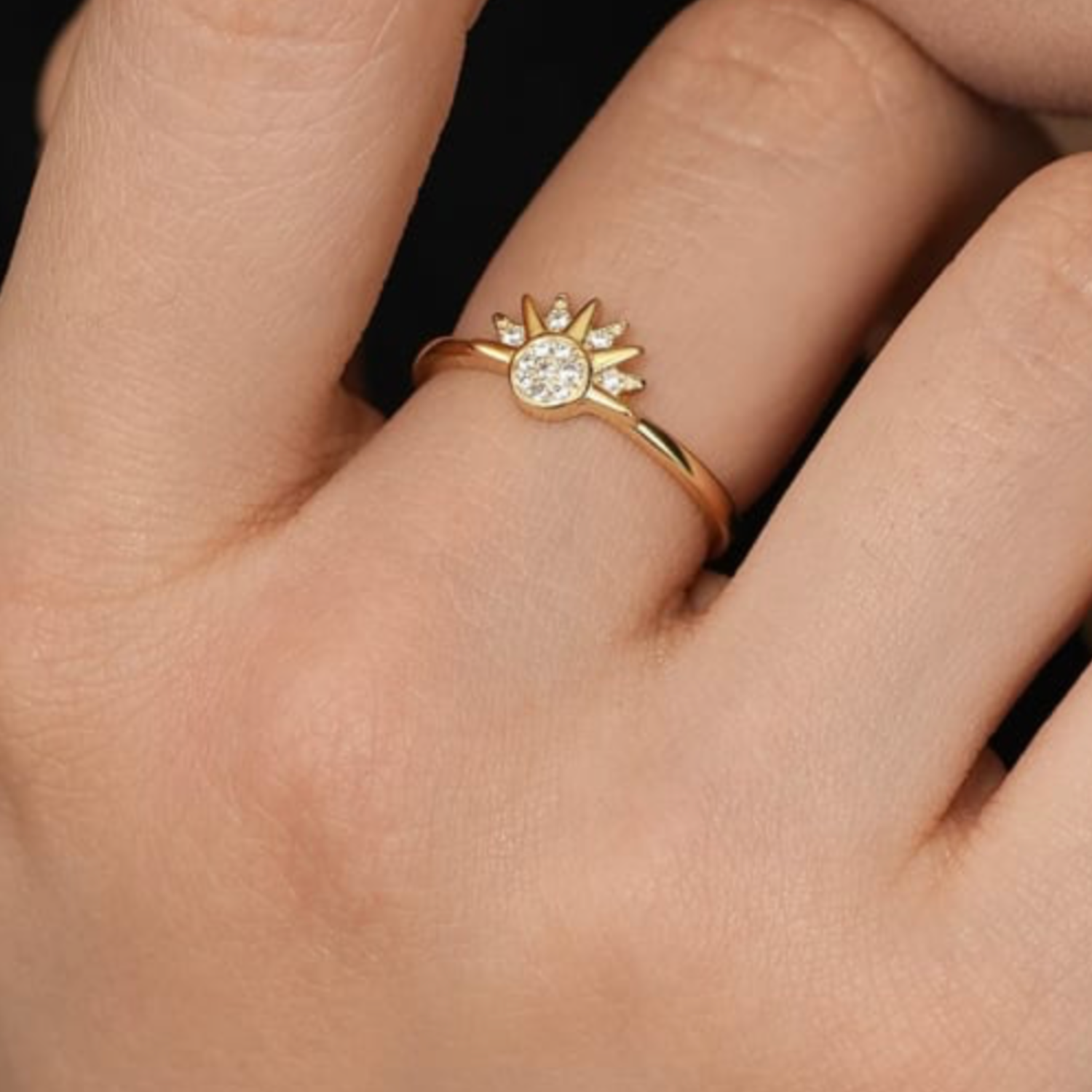 Gold ring with a sun design on a person's finger