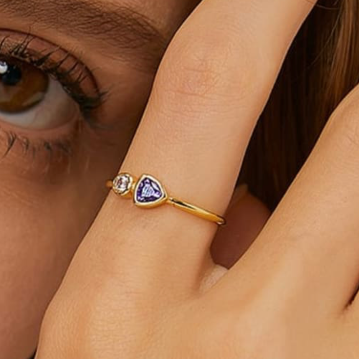 Gold ring with a heart-shaped purple gemstone on a person's finger