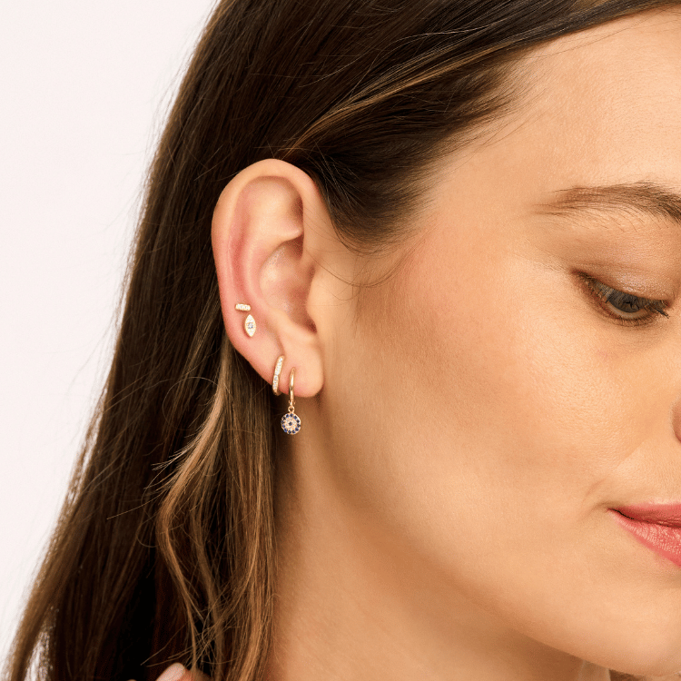 Model wearing Neptune Earrings – elegant blue pavé drop huggie earrings with shimmering blue stones on a sleek hoop, adding a touch of celestial charm