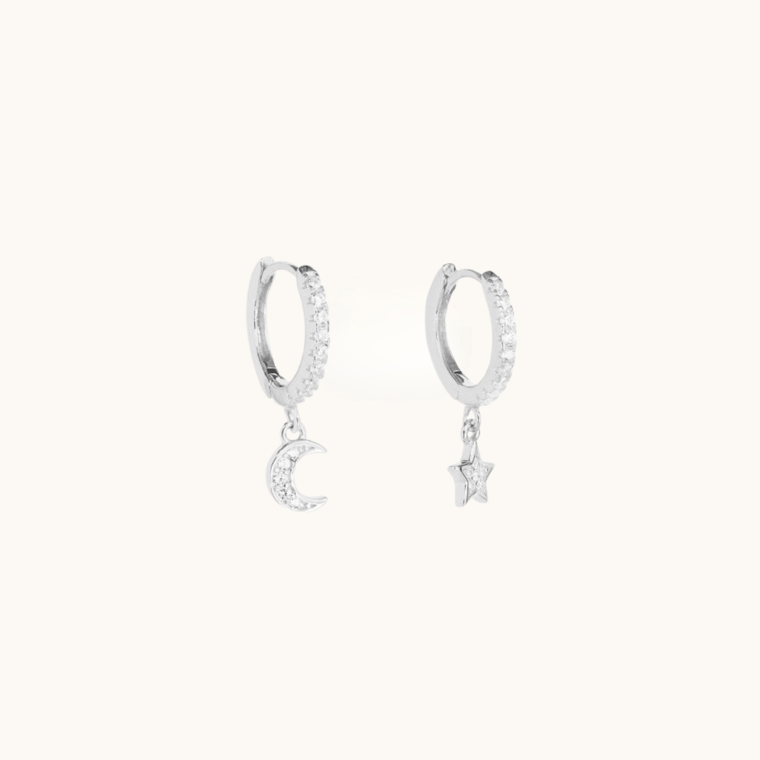 Silver hoop earrings with moon and star charms on a white background