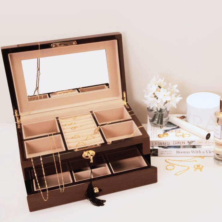 Open wooden jewellery box with jewellery inside, showing ring section, and compartments