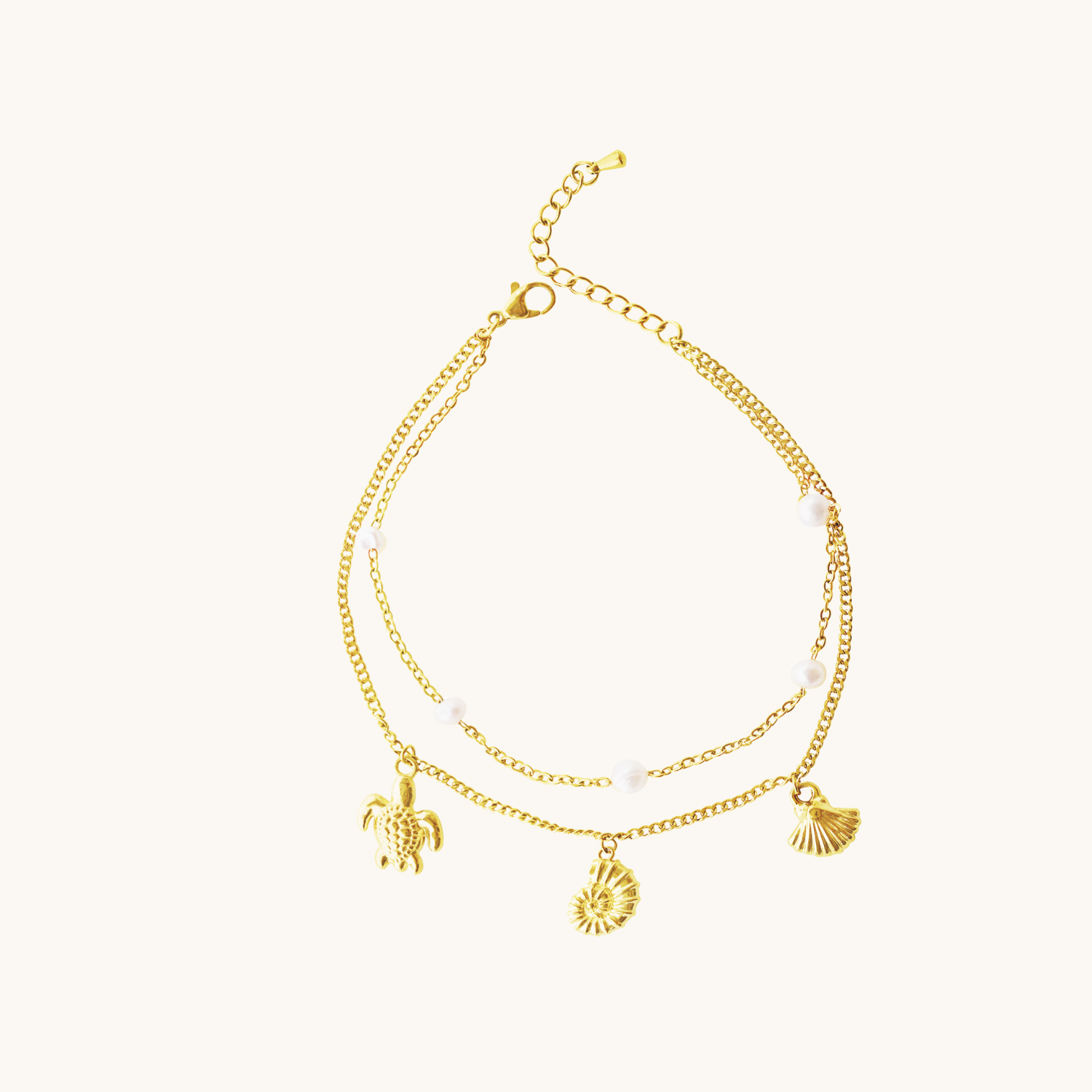 Two gold anklets with charms on a white background