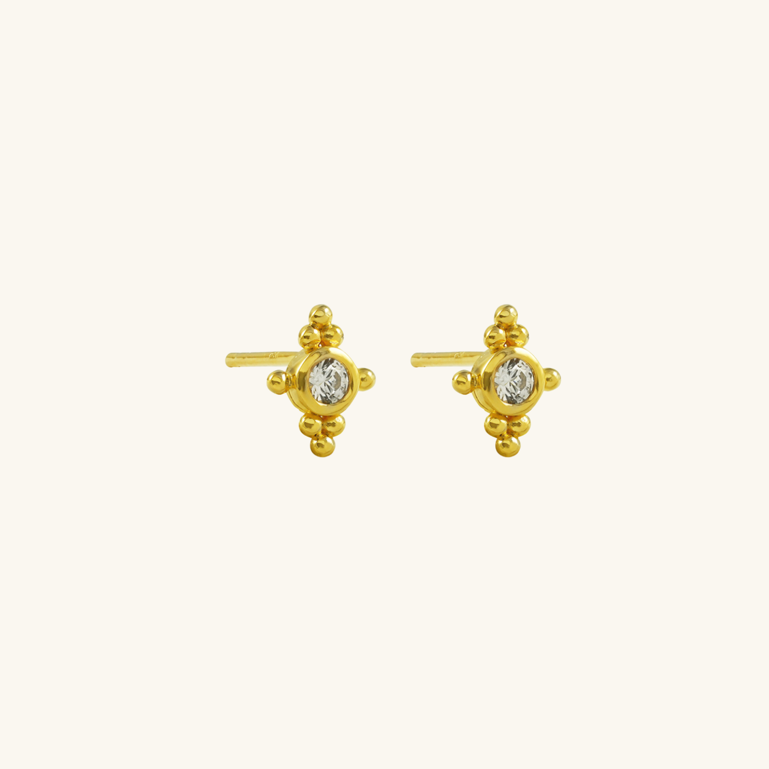 Gold plated earrings with diamond-like stones on a white background