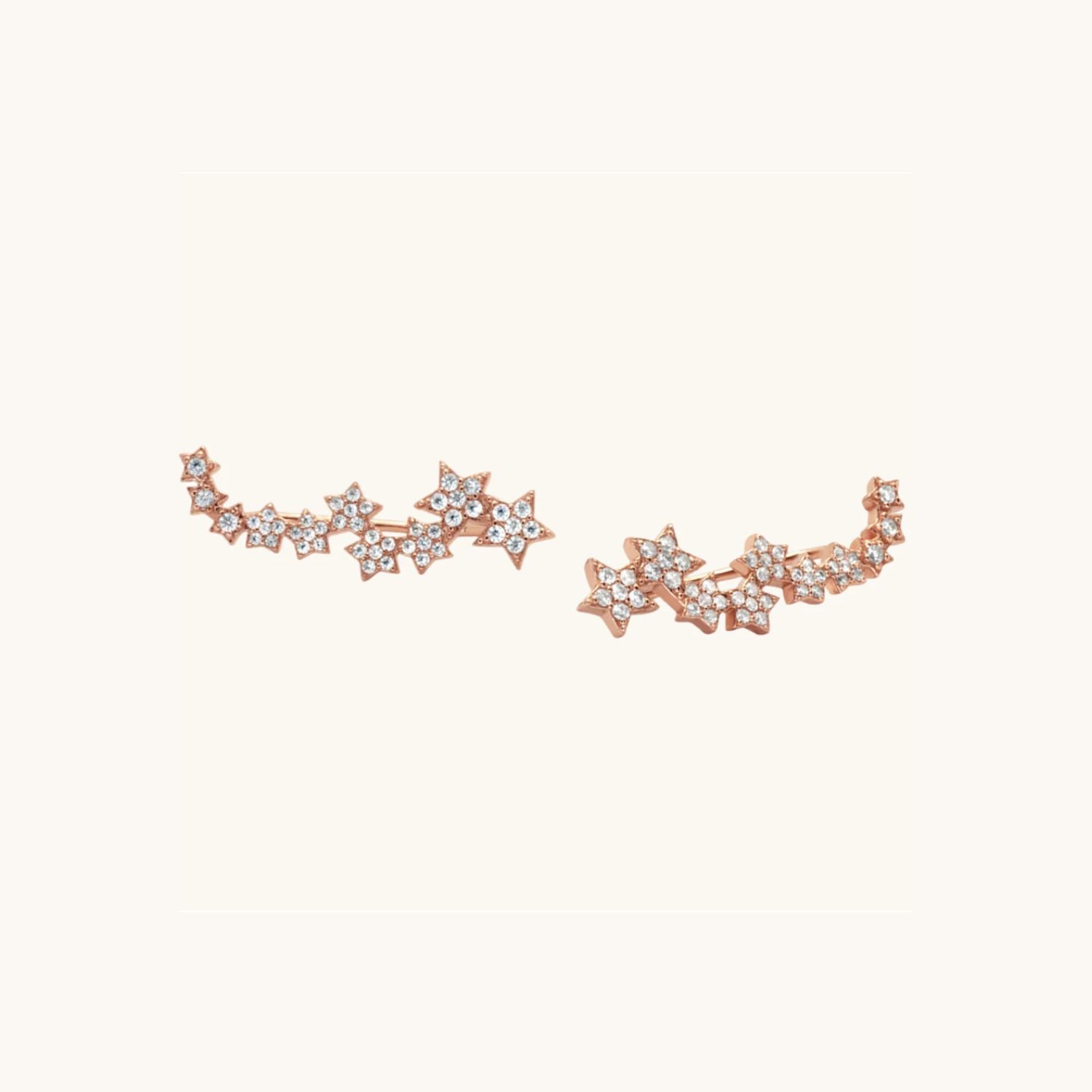 Star cuff Rose gold earrings that sit along the ear lobe. Displayed on cream background