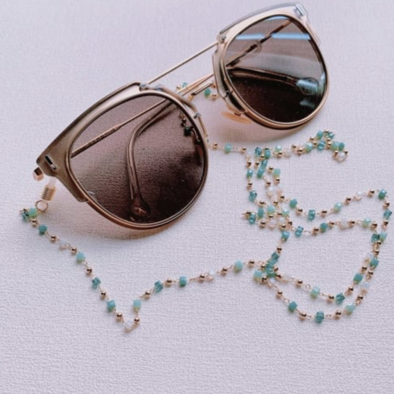 Sunglasses with a beaded chain on a light background