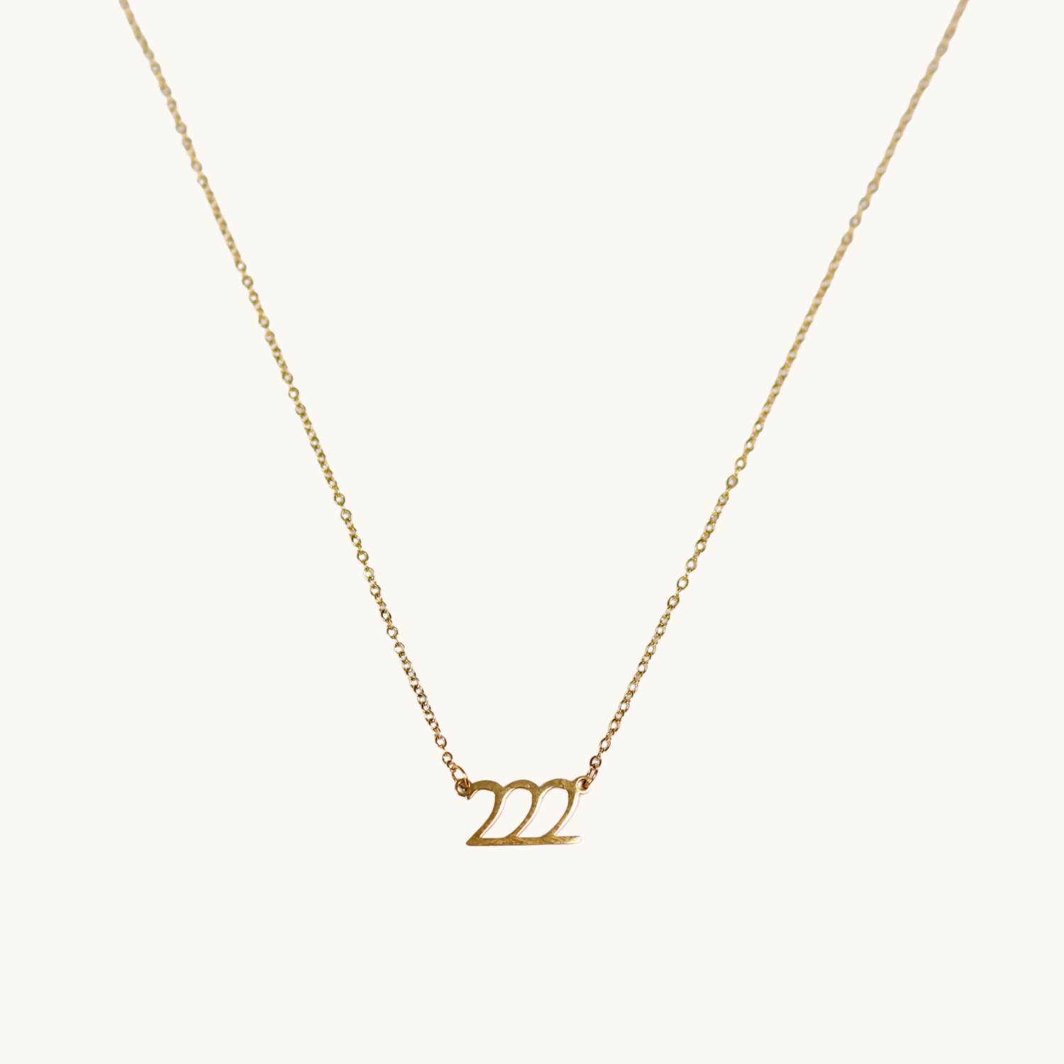 Gold necklace with '222' pendant on a white background