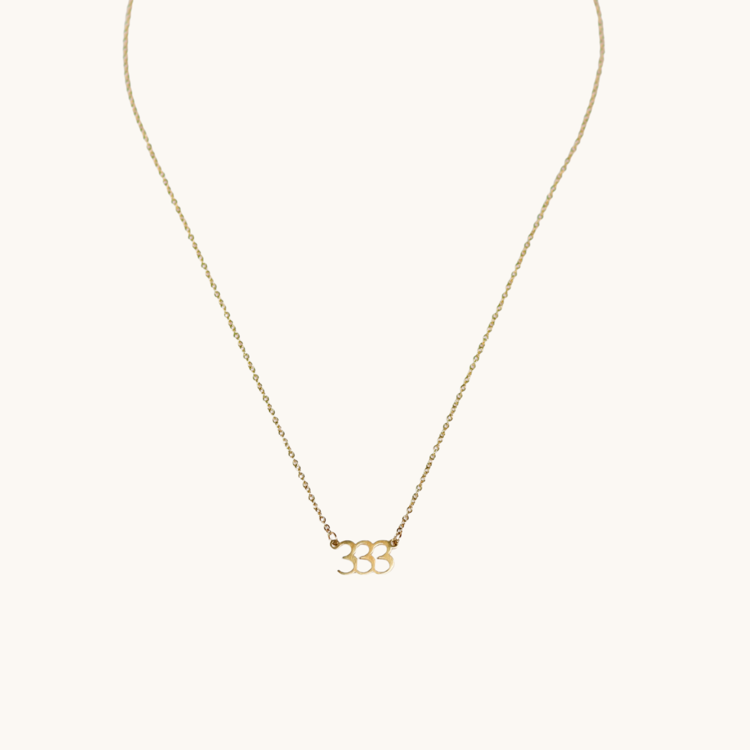 Gold triple 3 necklace on a white background