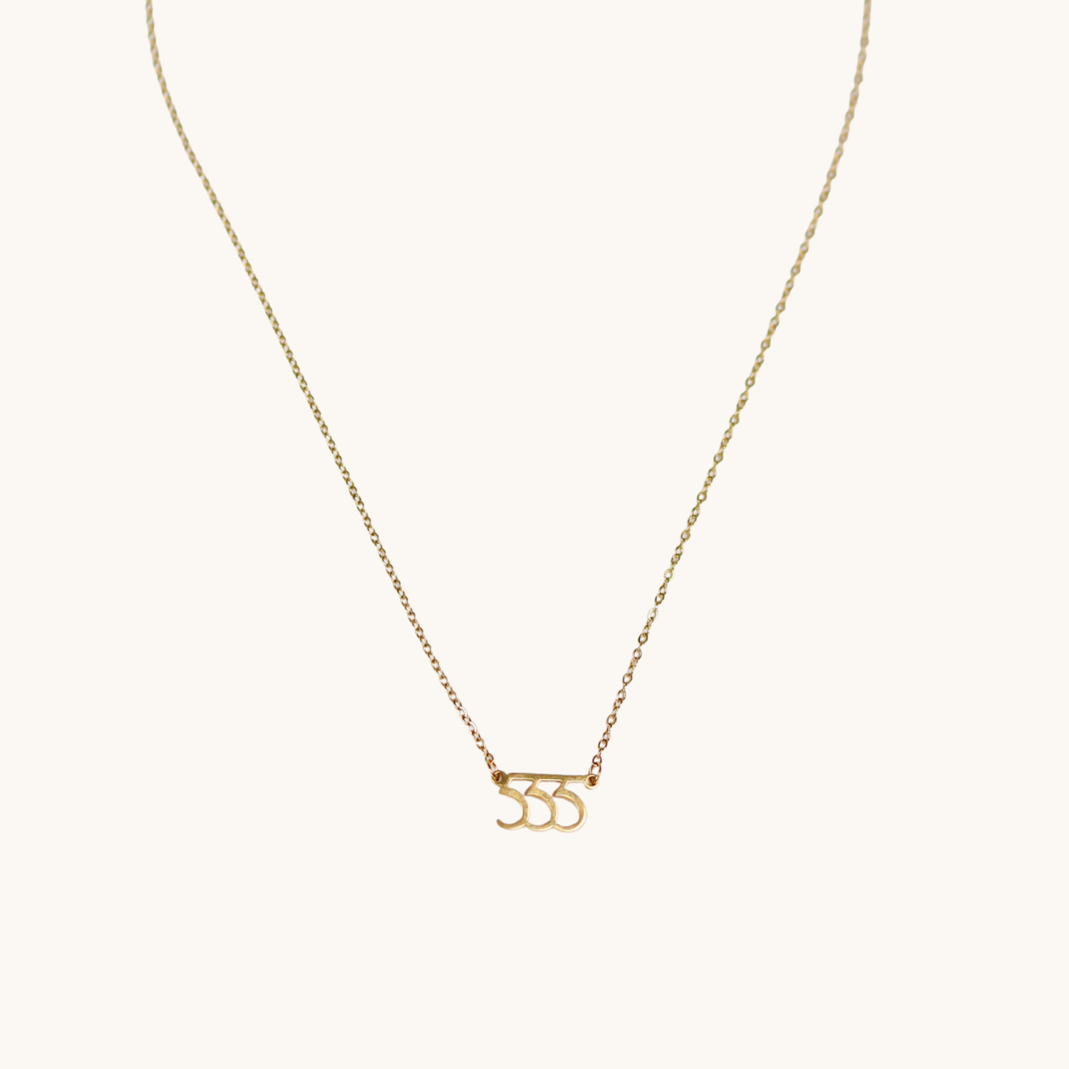 Gold necklace with a '555' pendant on a white background