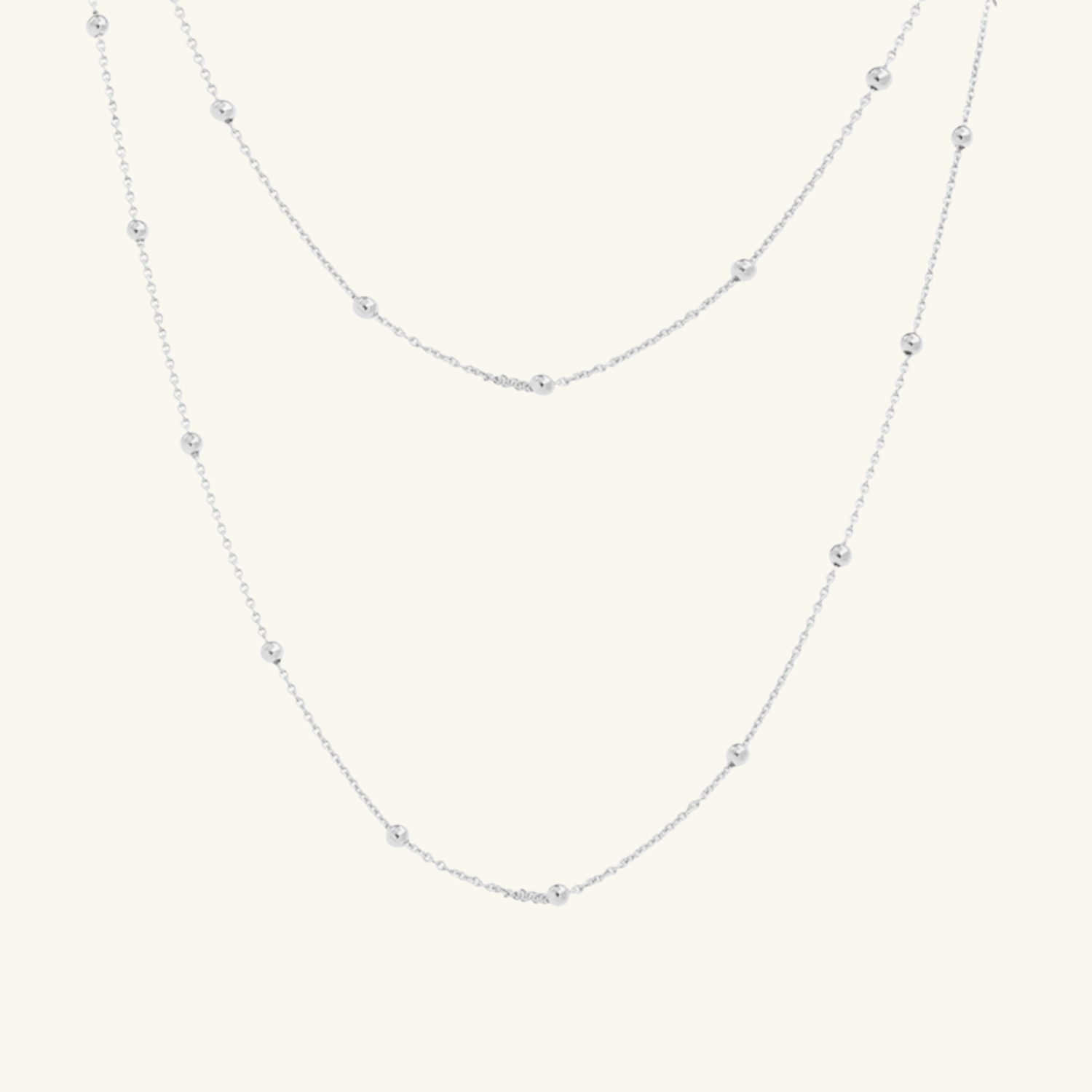 Silver necklace with small beads on a light gray background