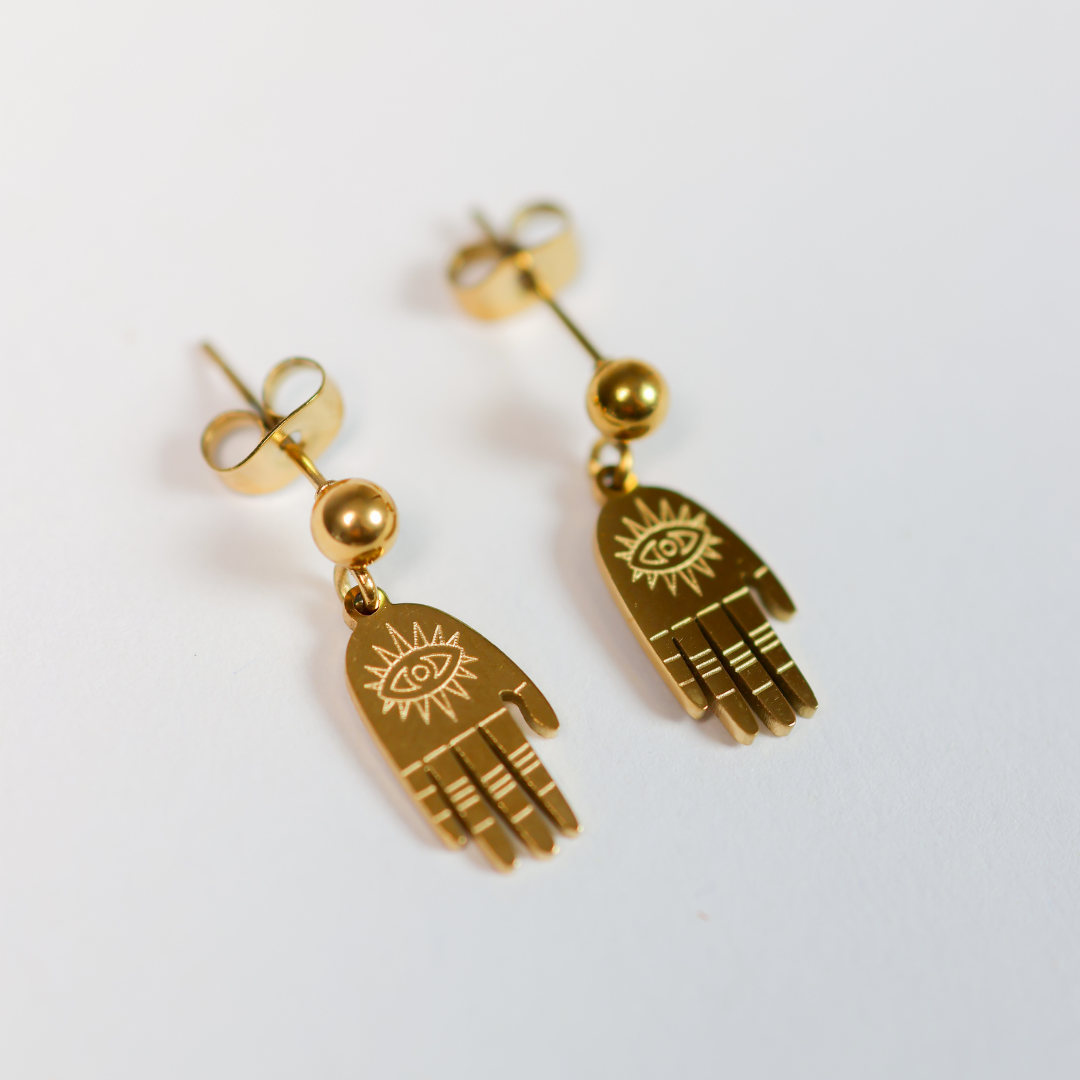 Gold hand-shaped earrings with evil eye design on a white background