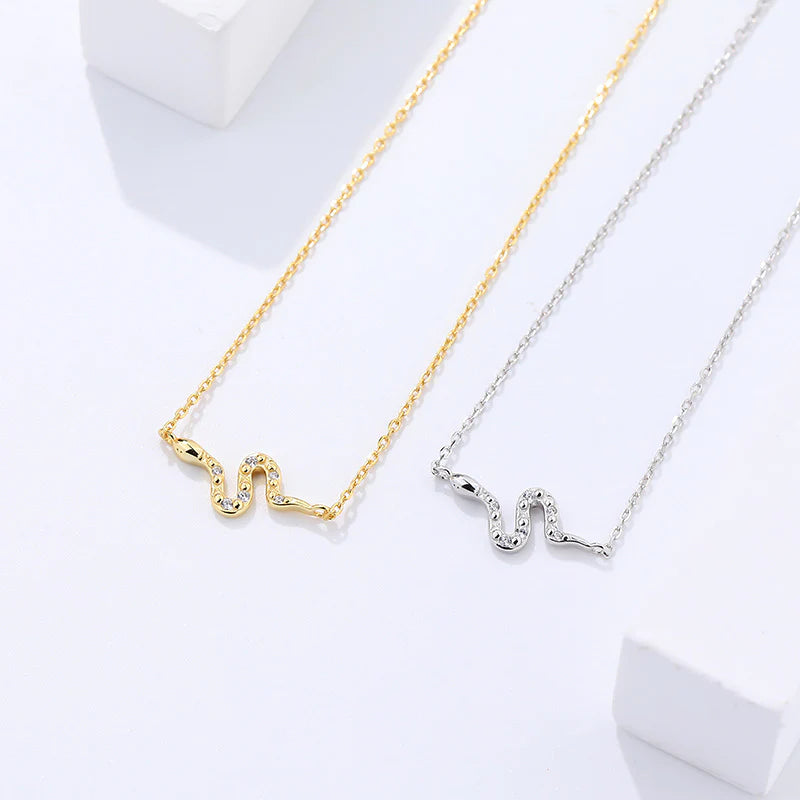 Image showing snake necklace in gold placed next to silver snake necklace on white background