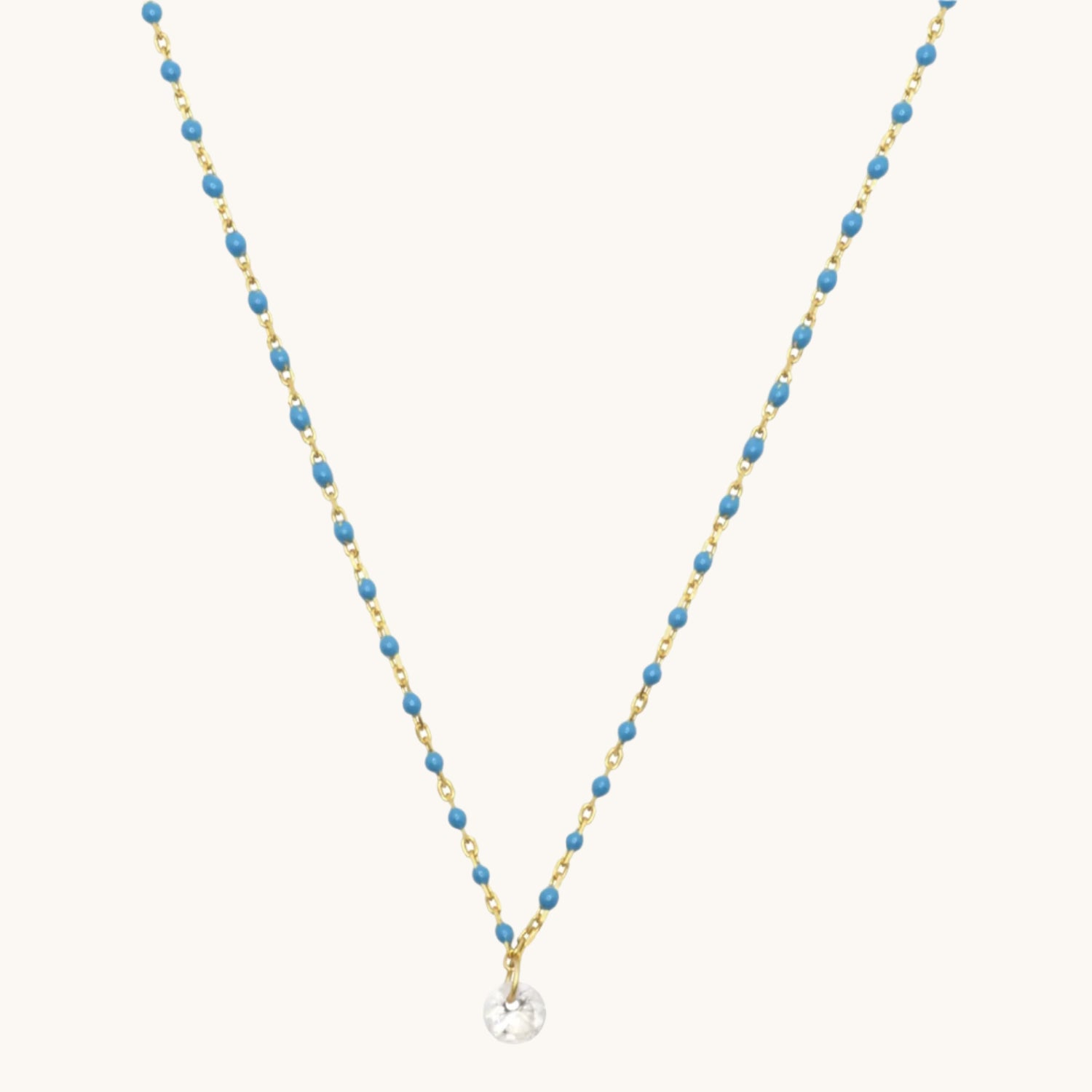 Blue enamel with cubic zirconia drop necklace pictured on cream background