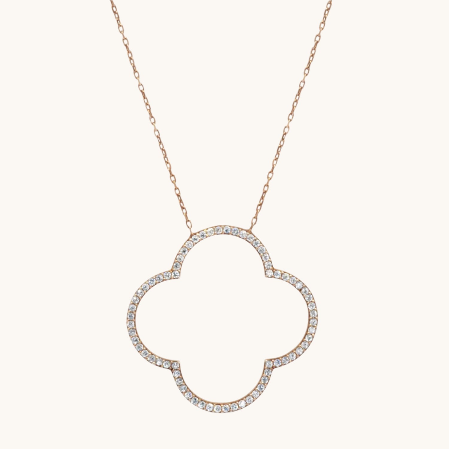 Four-Leaf Clover Necklace Encrusted with Cubic Zirconia in gold plated, on a cream background