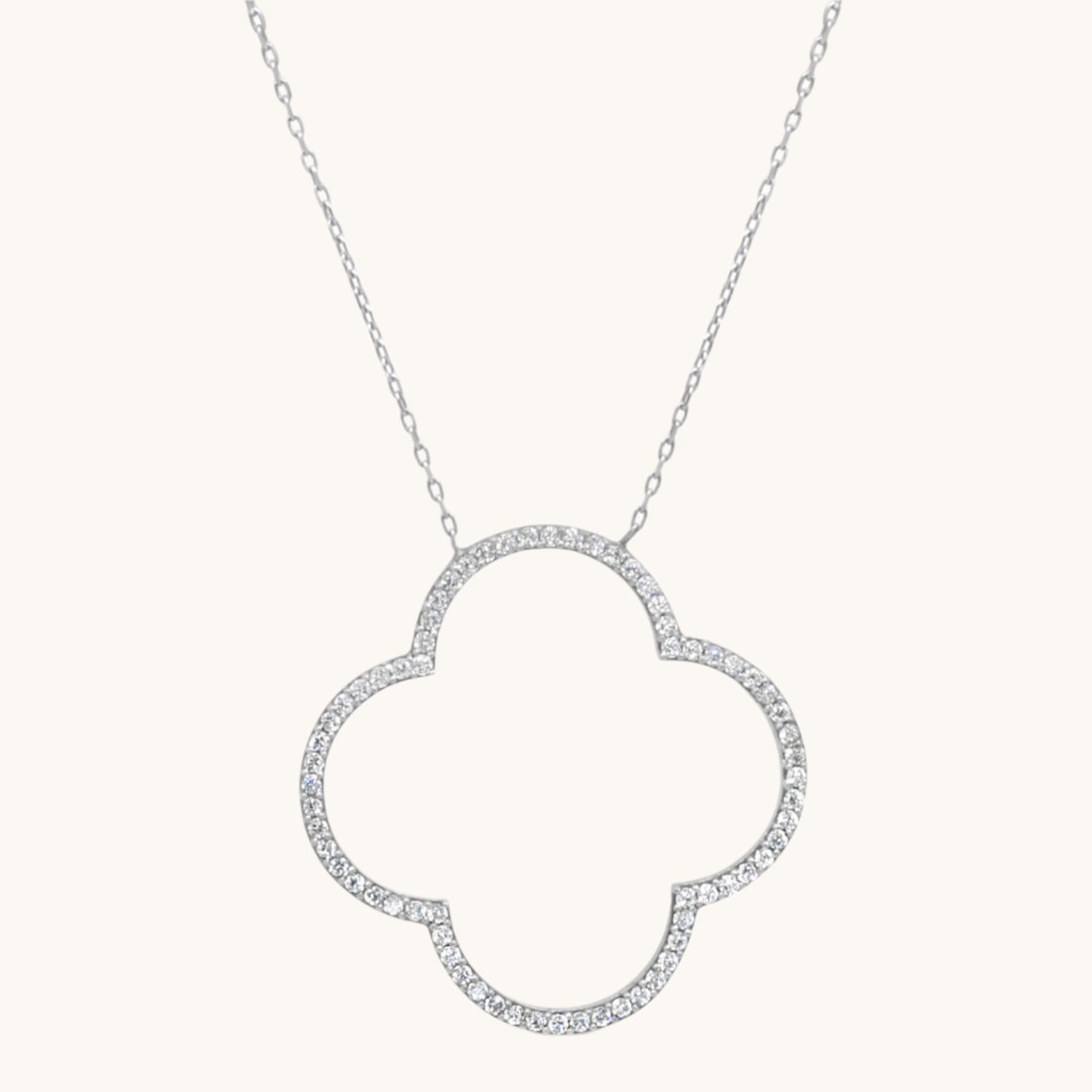 Four-Leaf Clover Necklace Encrusted with Cubic Zirconia in sterling silver on warm cream background