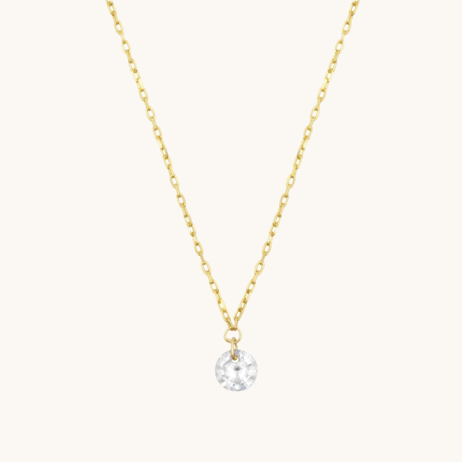Gold Single cubic zirconia drop necklace on warm cream background