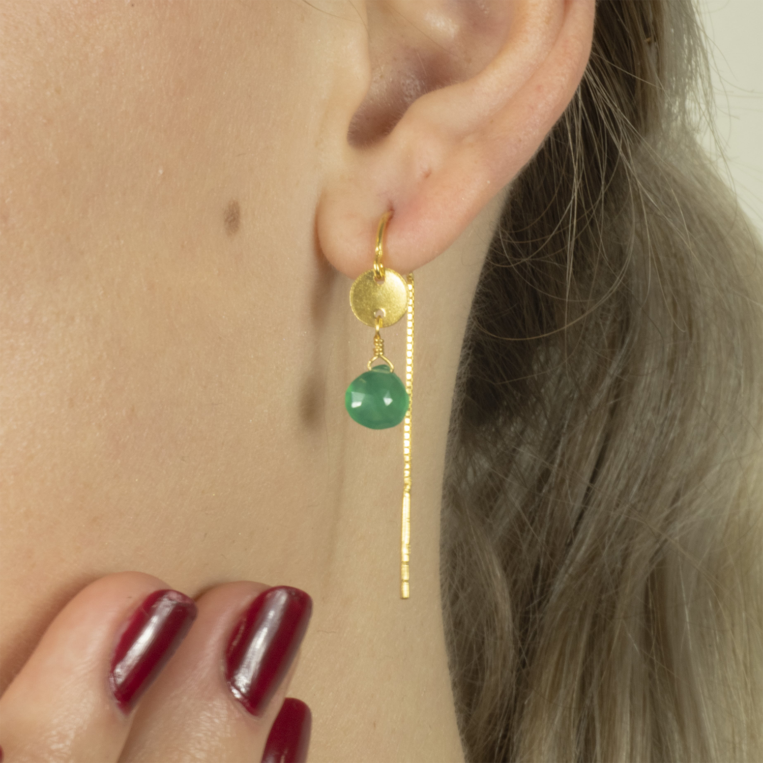 Model wearing green drop gold earrings