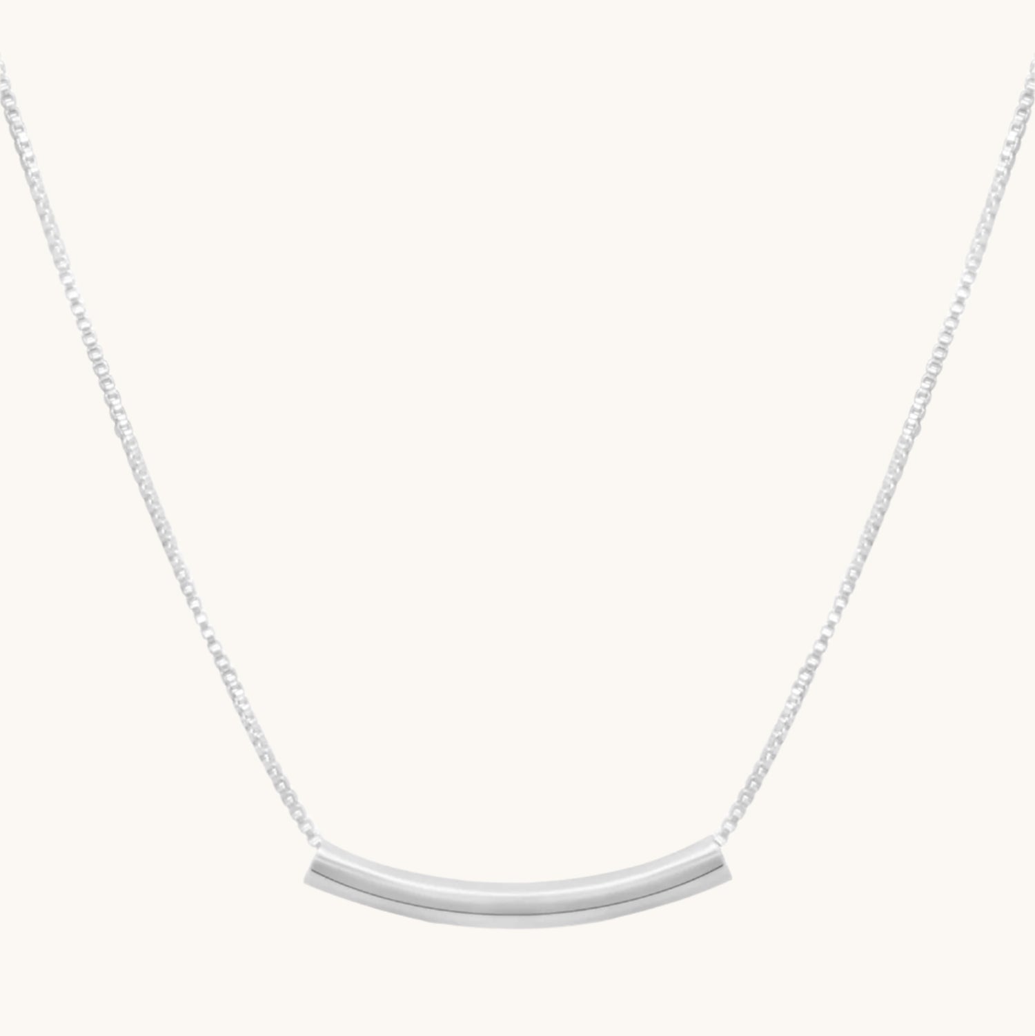 Silver necklace with curved bar detail on cream background