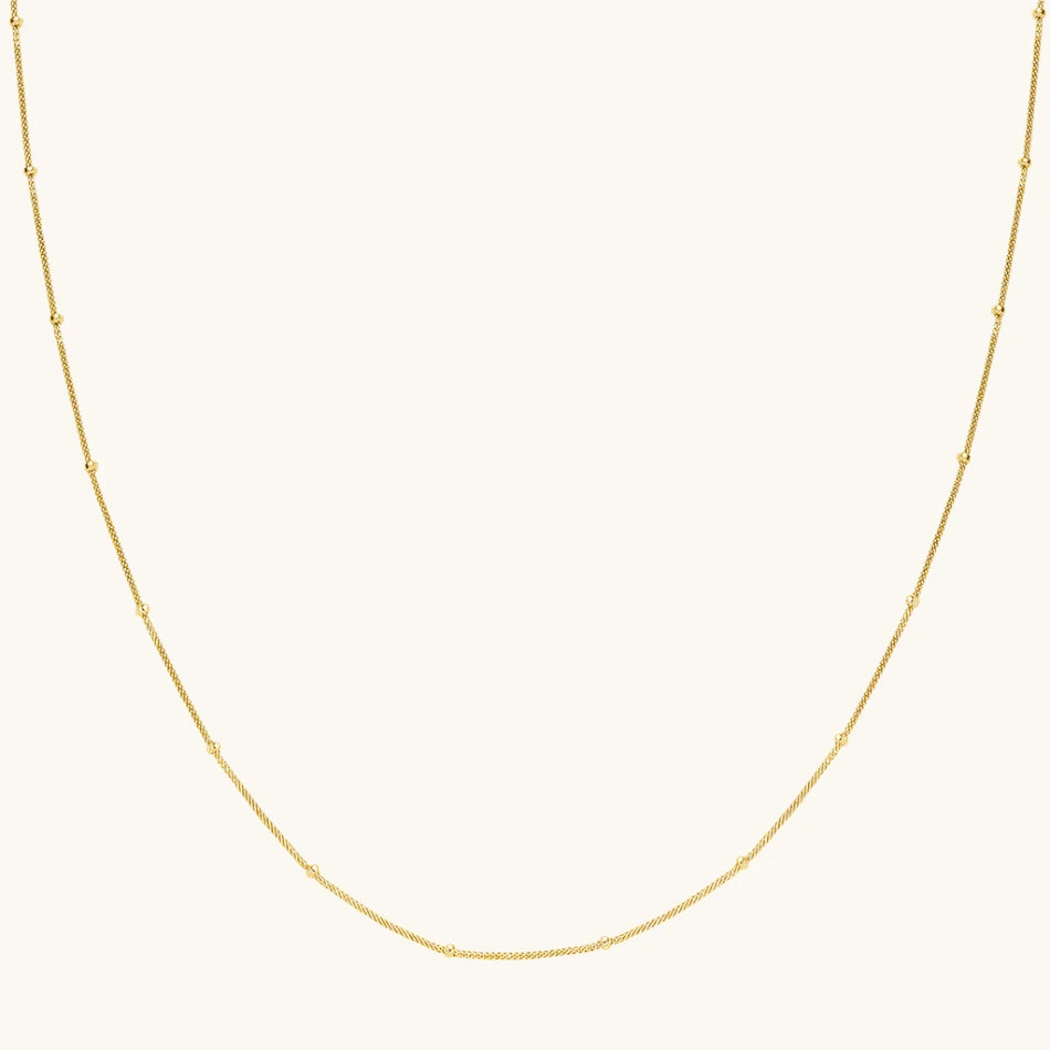 Simple gold satellite necklace on cream background
