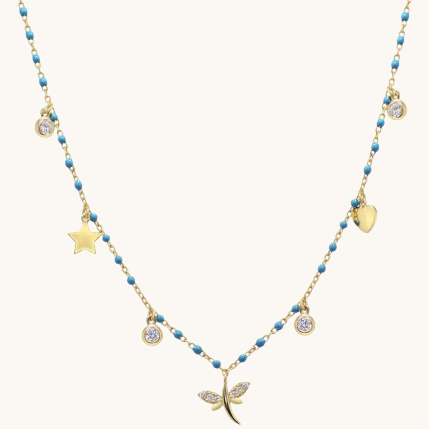 blue and gold charm necklace with cubic zirconias on cream background