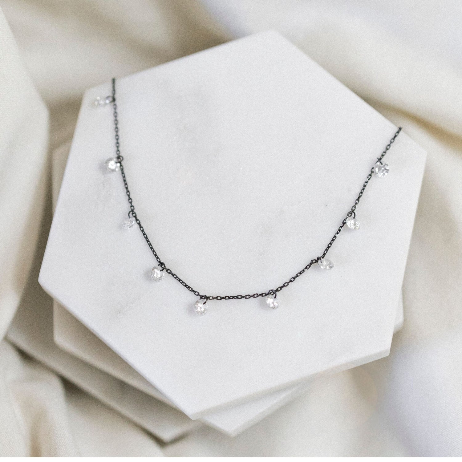 Pretty Cubic Zirconia Drop Necklace with black chain pictured on ceramic tile