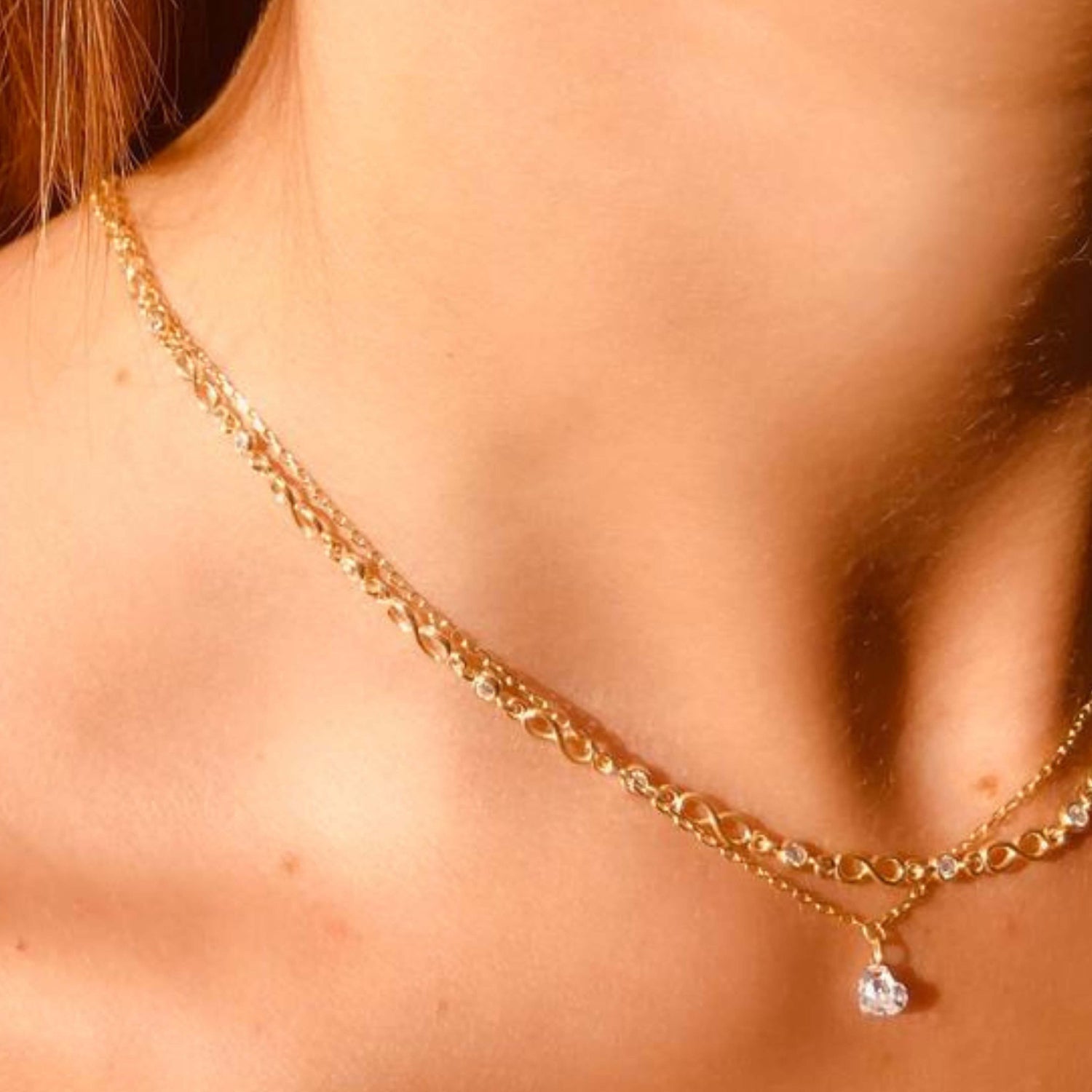 model wearing infinity symbol and Cubic zirconia necklace, stacked with single cz drop necklace