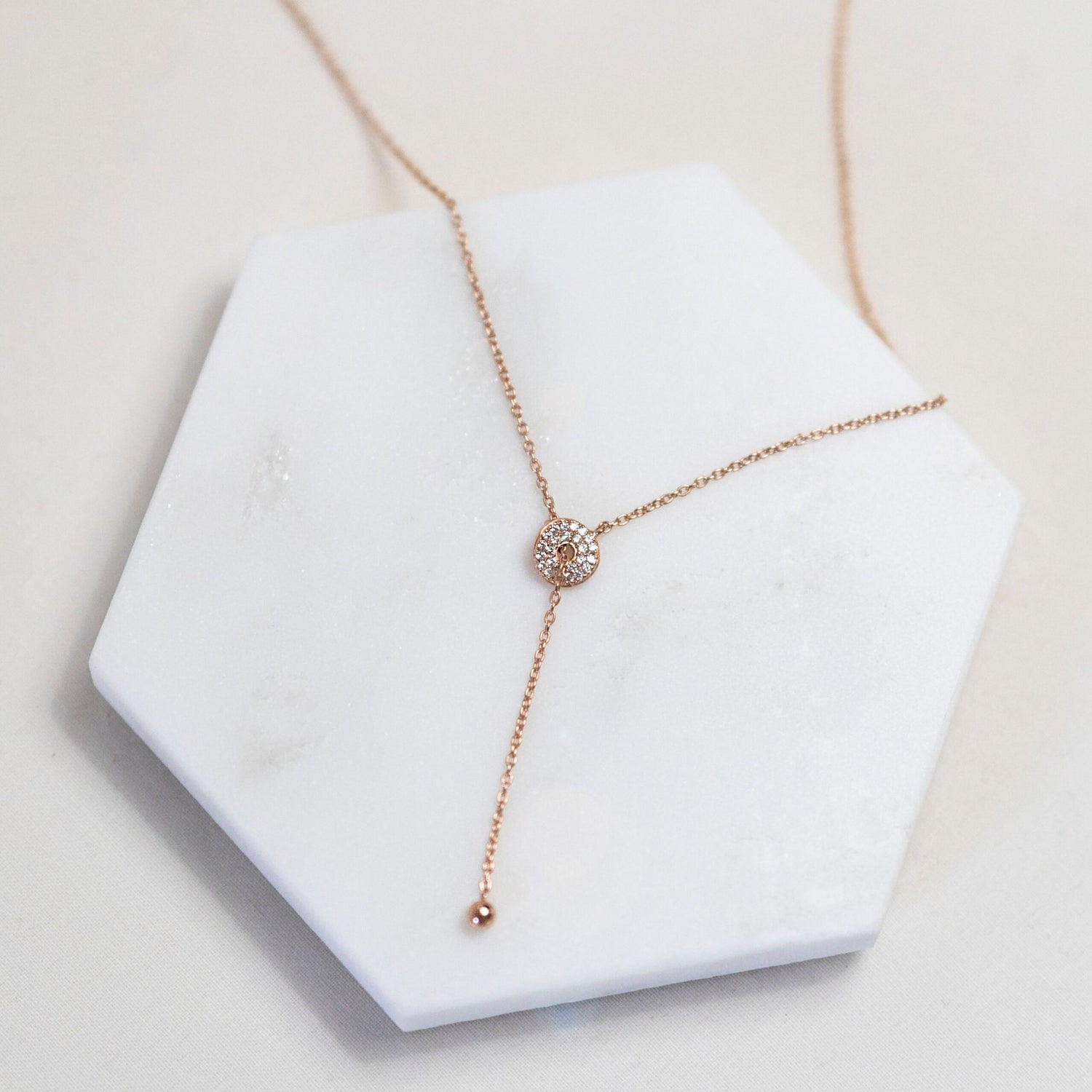 Stunningly Simple gold plated Lariat Necklace laid out on a tile
