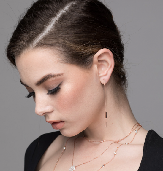 Model wears thread and rectangle drop earrings in rose gold