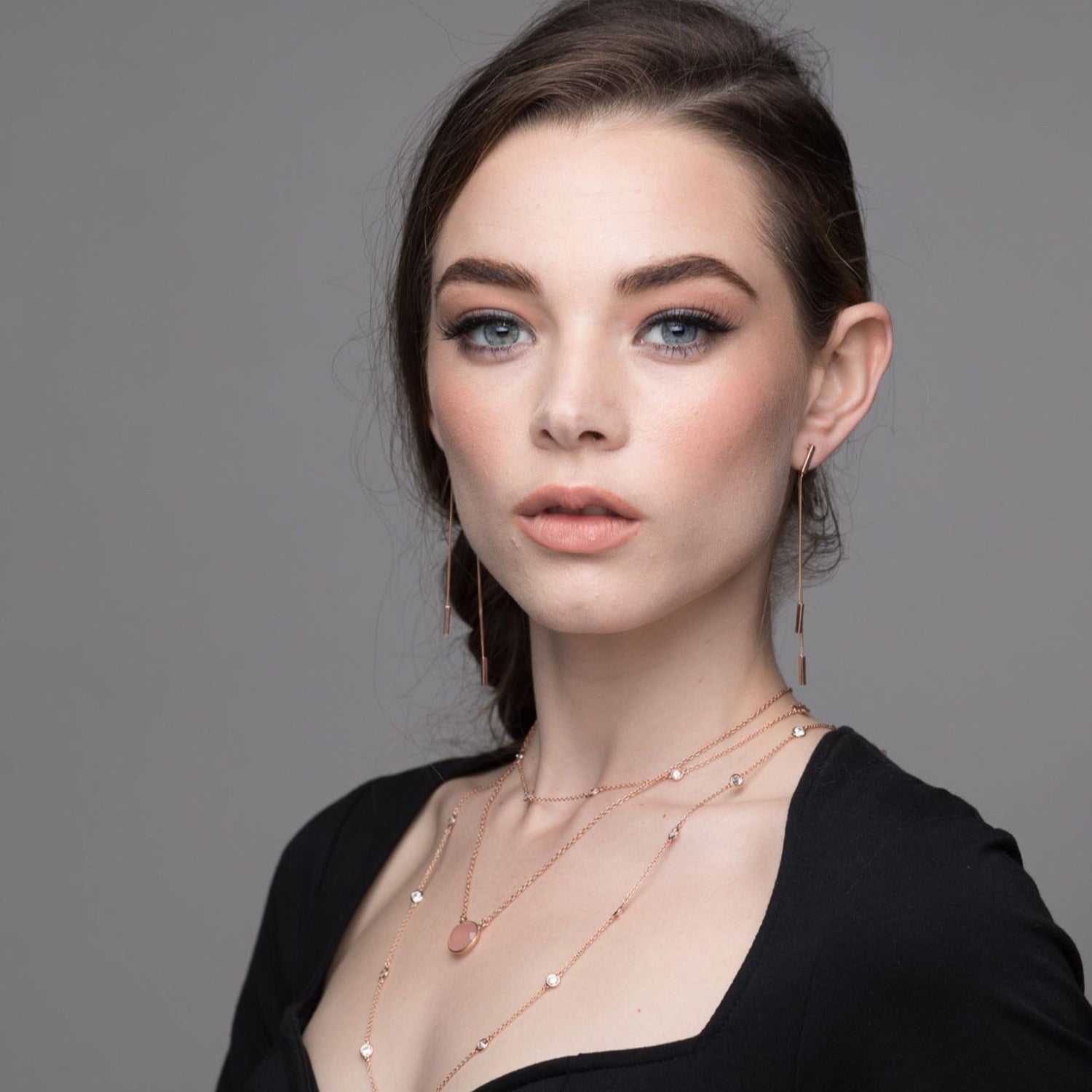 Model wearing single pink semi-precious stone necklace in rose gold plated layered with other pieces