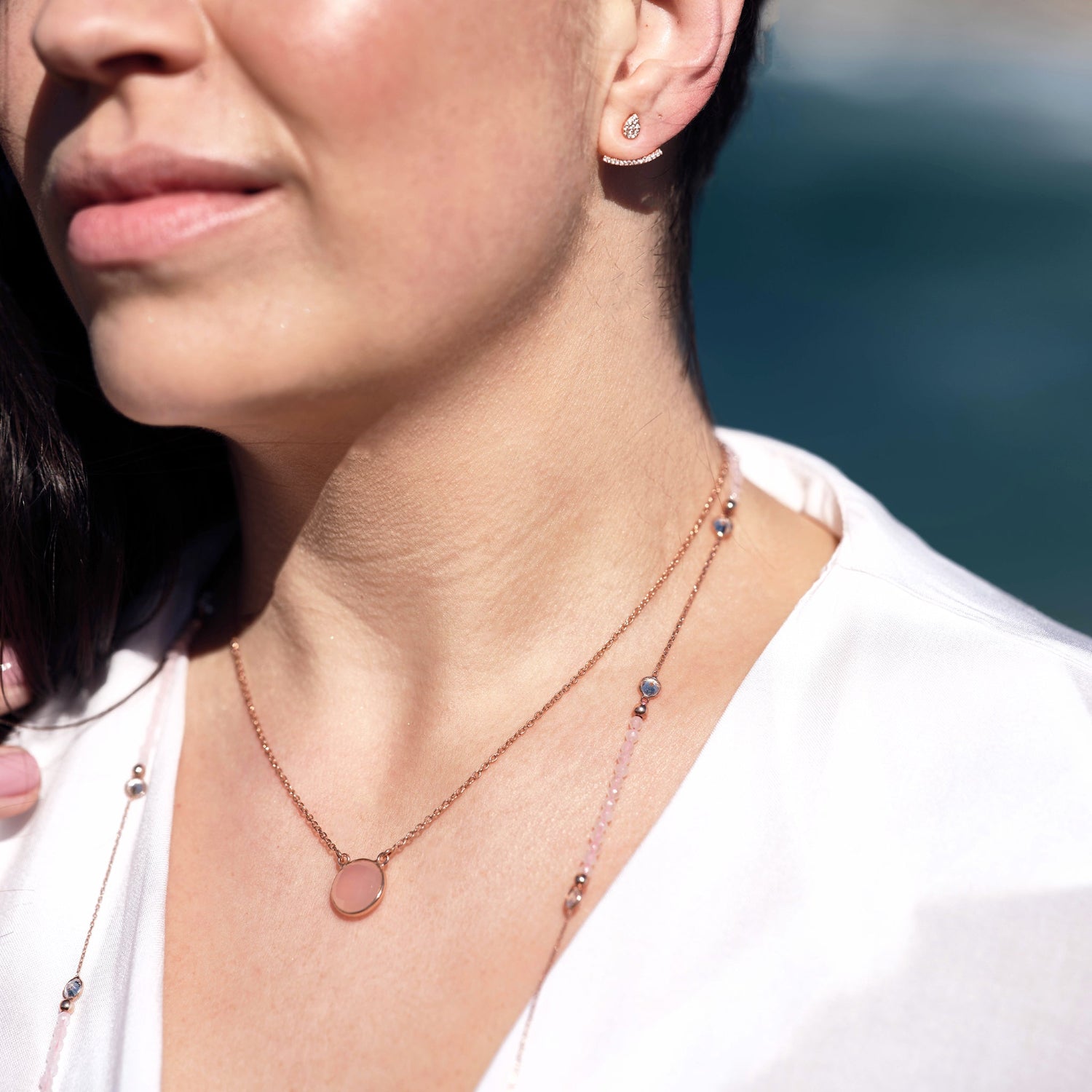 model wears necklace with semi-precious pink stone layered with a longer necklace