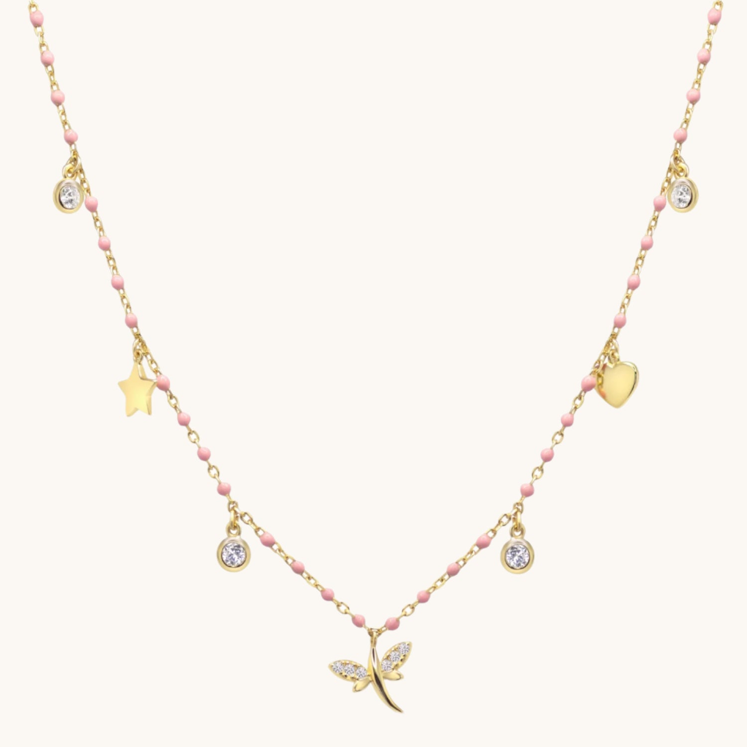 Pink and gold charm necklace with Cubic zirconia on cream background
