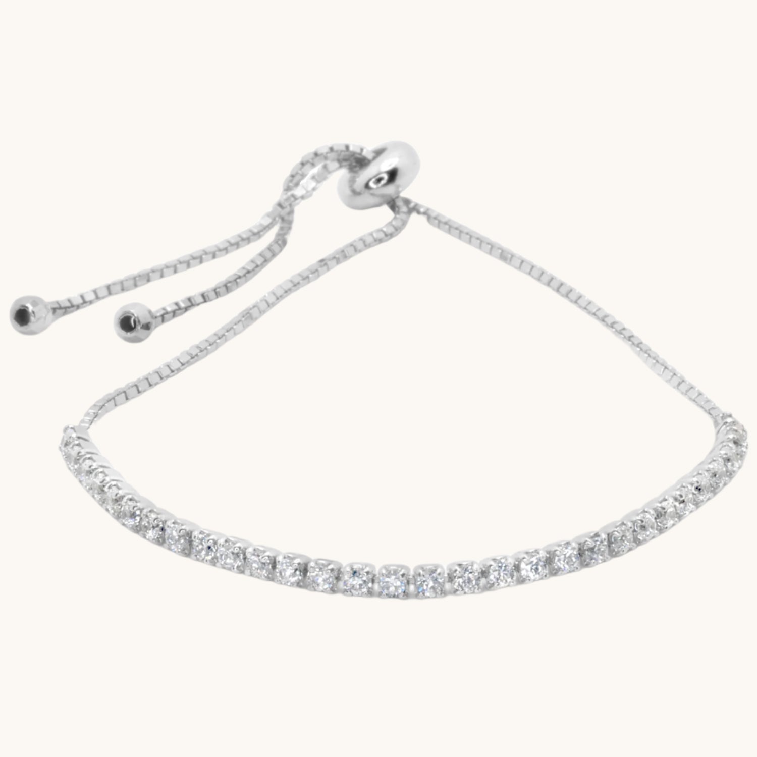Silver cubic zirconia tennis bracelet flat lay on soft cream background